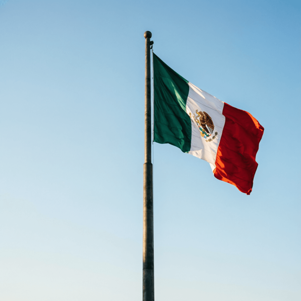 Bandera de México ondeando en un mástil con cielo despejado